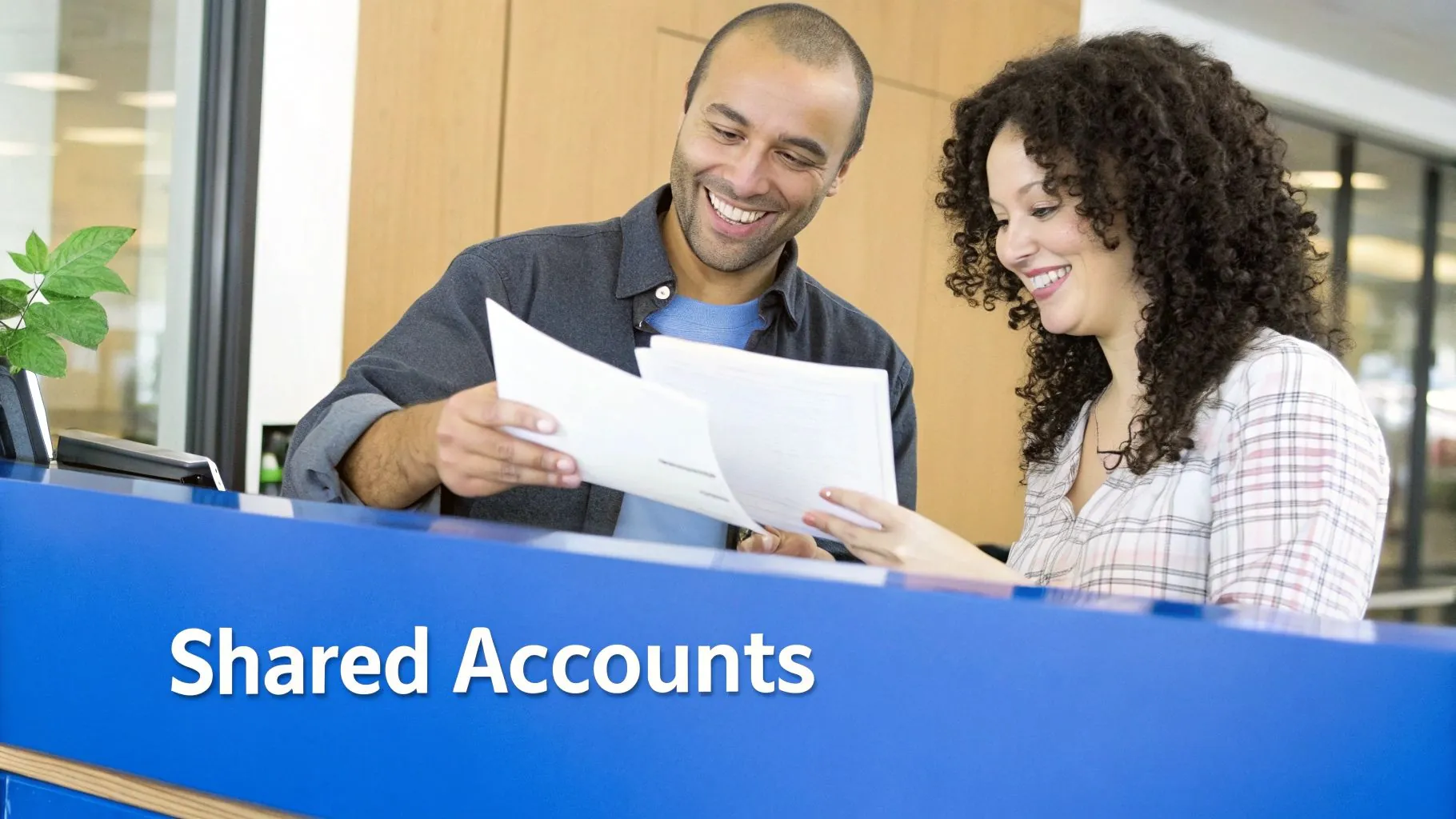 A couple sitting on a living room floor, surrounded by moving boxes, looking at a laptop and smiling.