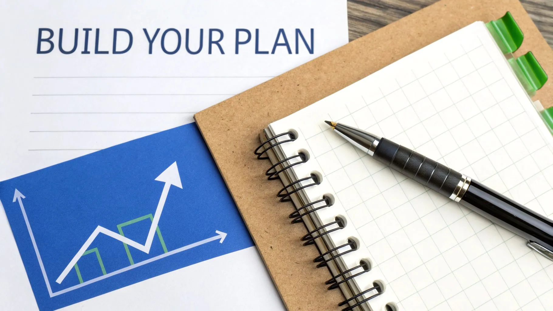 A person is sitting at a desk with a laptop, calculator, and notebook, creating a financial plan based on their net worth results.